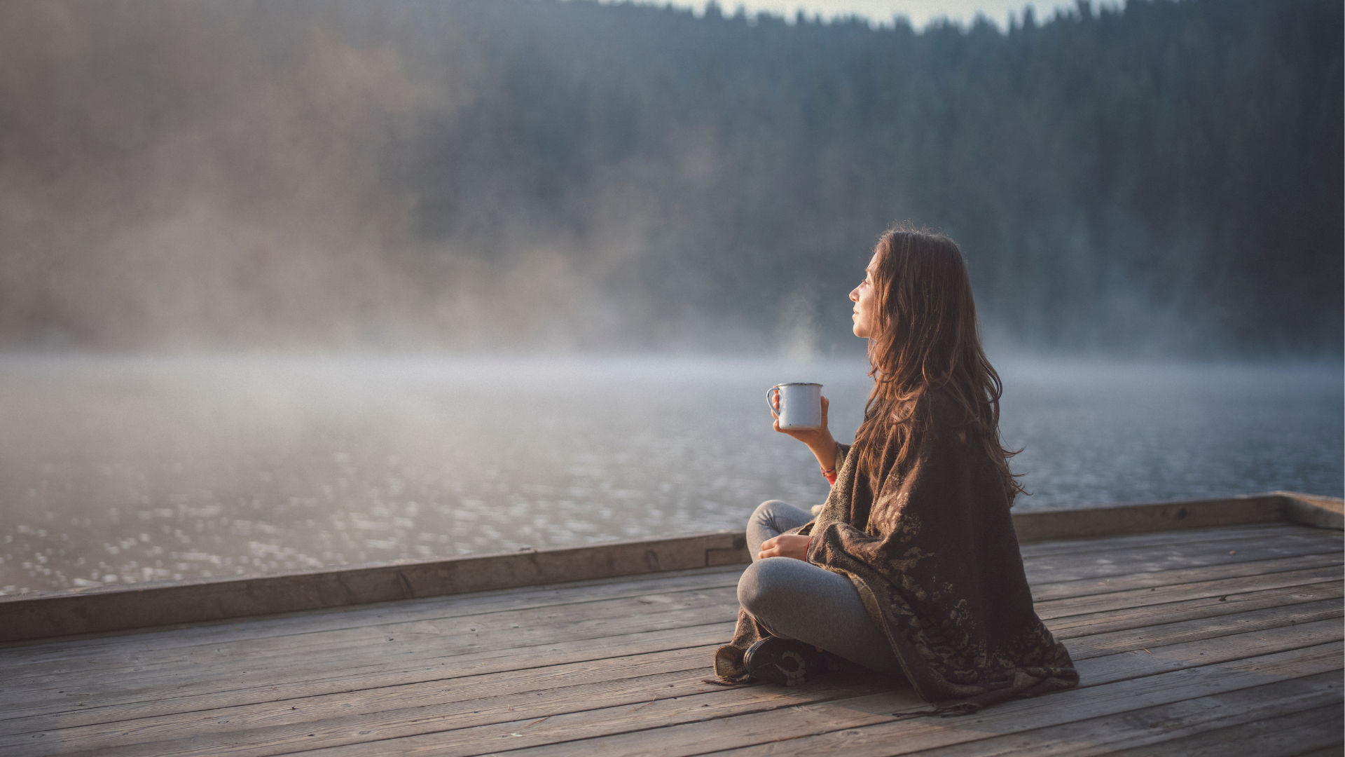 Une femme bois un thé au bord du lac embrumé